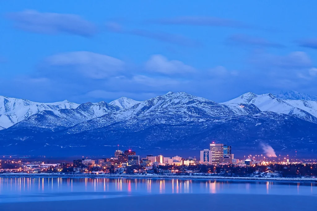 the skyline of anchorage alaska with snowy mountains and the city lights on